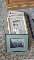 Four framed art prints on floor, three white-framed by Sue Coleman and one teal frame with aquatic scene