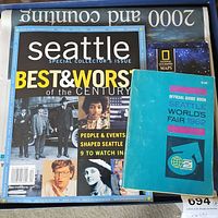 Top-down view of the collection showing the Official Guide Book Seattle World's Fair 1962, National Geographic World maps, and a Seattle collector's issue magazine.