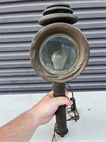 Round antique car lamp front showing glass lens and electric bulb
