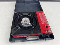 Full view of the Thunder Range portable butane stove inside fitted carrying case, showing burner and metal support grate.