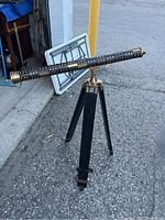 Full view of brass and mahogany telescope mounted on dark wooden tripod outdoors.