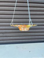 Full view of the hanging glass fruit dish suspended by three metal chains, showing the multicolor speckled glass pattern and dish shape.