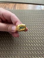 Two photos showing a gold plated Houston Astros championship ring held between fingers. The ring has 'World Champions' inscription and the team logo in colored enamel on the face.