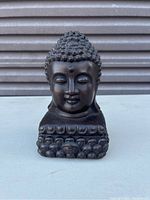 Front view of dark brown pottery Buddha head with detailed curls and lotus base.