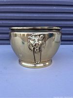 Front angle view showing the brass planter exterior and lion head detail with ring.