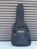 Front view of black soft fabric Martin & Co. guitar case with visible logo and front zippered pocket.