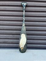 Front view of wooden painted paddle with detailed owl image.