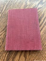 Front cover of the pocket-sized Moby Dick book showing maroon cloth cover with embossed whale symbol.