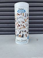Cylinder-shaped Ridley's jigsaw puzzle packaging featuring illustrations of many dog breeds and the title 'The Dog Lover's Jigsaw Puzzle'.