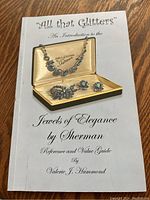 Cover of the book titled 'All that Glitters' - An Introduction to the Jewels of Elegance by Sherman. Shows jewelry set on cover.