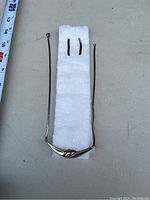 Photo showing sterling silver necklace with curved center and matching earrings placed on white padding alongside measuring tape.