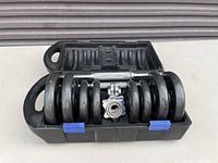 Weight plates and dumbbell bars with collars inside an opened carrying case