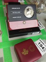 Front view of the coin housed in an official Royal Canadian Mint black and maroon case, with text Sterling Silver, 30 Dollars, Argent Sterling