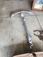 Full top-down view of the heavy cast iron anchor lying on concrete floor, showing the entire length and shape of the anchor.