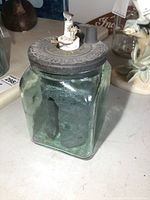 Front side of the green glass wet cell battery showing the square body and lead plates inside.