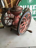 Three-quarter view of red cast iron grinder with twin decorative wheels