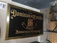 Full view of rectangular vintage metal sign with black background and gold trim and lettering.