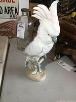 Front angle photo of the white porcelain cockatoo figurine showing detailed feathers, crest, beak, and base with leaves.