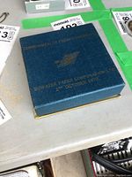 Blue presentation box for The Armada Dish, showing gold embossed text with date and company name.