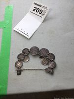 Full view of vintage silver coin bracelet with multiple linked coins and safety chain.