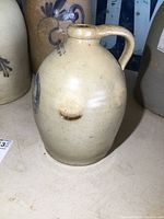 Front view of the jug showing the beige stoneware body with a handle and a blue floral design.