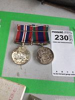 Pair of circular sterling silver Canadian WW2 medals with original ribbons, showing signs of wear and fraying.