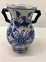 Close-up view of porcelain vase showing blue floral design and two blue handles.
