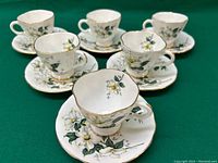 Set of 6 Windsor tea cups and matching saucers, white with yellow and white floral design and gold trim.