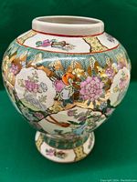 Front view of a rounded vintage Chinese vase with colorful floral and bird painted designs and gold accents on a white ceramic body.