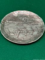 Top view of circular metal tray showing detailed racecar track scene with grandstands and cars.