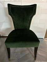 Front view of green velvet occasional chair with nailhead trim and dark wooden legs
