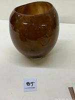 Photo of a brown Murano glass vase showing its rounded shape and glossy finish against a white background.
