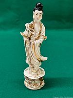 Front view of the vintage porcelain Kuanyin figurine standing on a lotus base with gold accents.