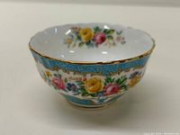 Front and slightly angled view showing floral decoration, blue background, and gold trim