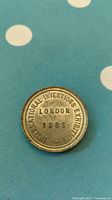 Obverse side of the 1885 International Inventions Exhibition medal showing circular inscription 'INTERNATIONAL INVENTIONS EXHIBITION LONDON 1885'