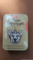 Front view of sealed Happy Birthday Dog Birthday Kit metal tin box with dog illustration.