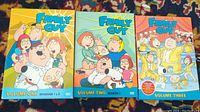 Front cover of three Family Guy DVD volumes showing colorful illustrated cases with the main characters and volume/season information