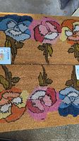 Two floor mats with flower design, showing full view of both mats with visible colors and texture.