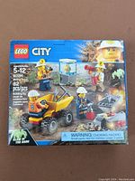 Front of the sealed LEGO City 60184 Mining Team box showing the set artwork, piece count, age recommendation, and glow-in-the-dark crystal feature.