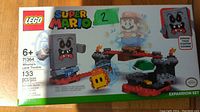 Front box view showing LEGO branding, Super Mario logo, set number 71364, and artwork of the Whomp character, lava platform, and Mario figure on clear stand.