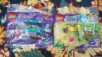 Two sealed LEGO Friends polybag sets 30413 and 30414 photographed on patterned carpet.