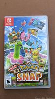 Front cover of game case for New Pokemon Snap showing colorful Pokemon artwork.