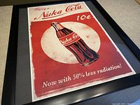 Framed Nuka Cola poster showing the full design with text and bottle.