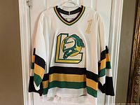 Front hanging view of white London Knights hockey jersey with stripes and large logo.