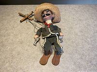 Full photo of the marionette doll lying on a surface showing the wooden body, cloth outfit, and attached wooden control crossbar.