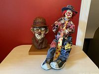 Pair of clown sculptures, one bust on wooden base and one handmade figurine sitting in front