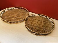 Pair of round nesting trays with woven wicker bases and metal frames shown side by side.