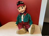 Front view of Pinocchio marionette doll sitting on a table showing face, clothing, and shoes