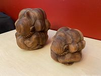 Photo showing two sugarwood weeping Buddha statues from a side angle against a red background