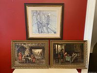Three framed vintage artworks hung on red wall: top artwork shows owl in tree, bottom left shows men playing cards outdoors, bottom right shows men playing chess indoors